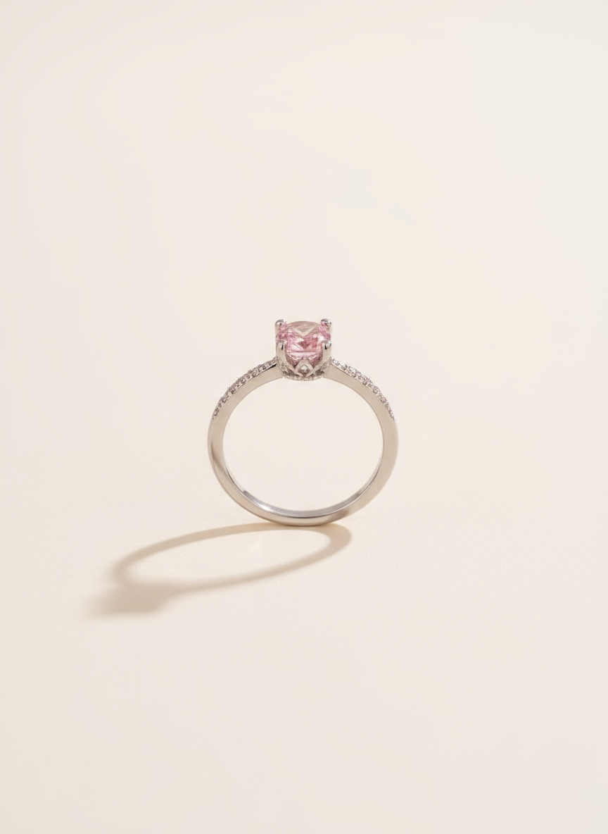 Silver ring with a pink gemstone on a light beige background