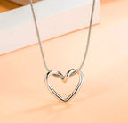 Silver heart-shaped necklace on a peach-colored background