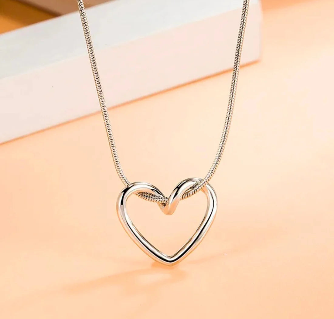 Silver heart-shaped necklace on a peach-colored background