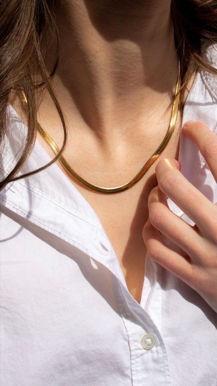 Person wearing a gold necklace with a white shirt